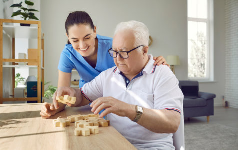 nurse assisting an elderly man in playing puzzle